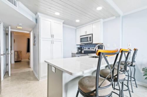 a kitchen with white cabinets and bar stools at Gulf Shores Surf & Racquet Club 212A in Gulf Shores