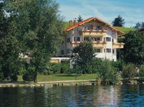 a large house sitting next to a large body of water at Gästehaus Guggomos "Hopfen am See" in Füssen