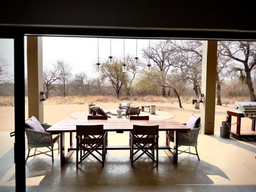 a dining room table with chairs and a large window at Mananga Bush Villa in Skukuza