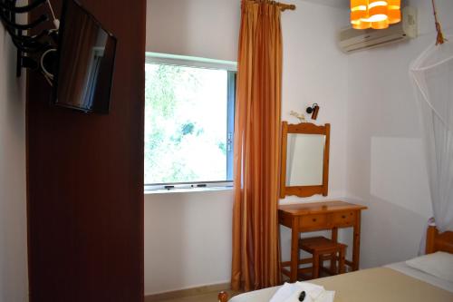a bedroom with a window and a table and a mirror at Kostas Apartments & studios in Agios Georgios Pagon