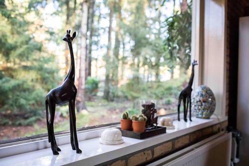 two statues of giraffes sitting on a window sill at Paulus aan de bos met hot tub in Epe
