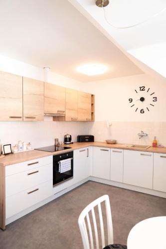 a kitchen with white cabinets and a clock on the wall at APARTMÁN U ZOUBKU in Litomyšl