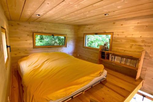une chambre avec un lit dans une cabane en rondins dans l'établissement Tiny à l'orée des bois, à Locquénolé