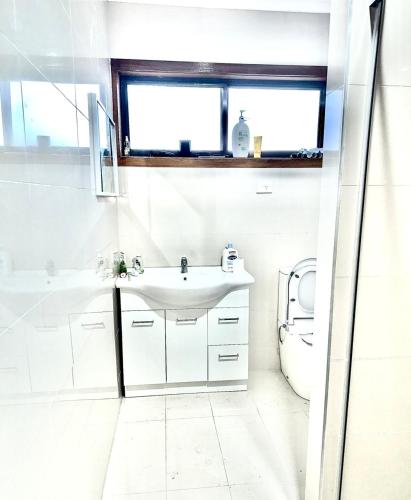 a white bathroom with a sink and a toilet at Guest Room in Kealba in St Albans