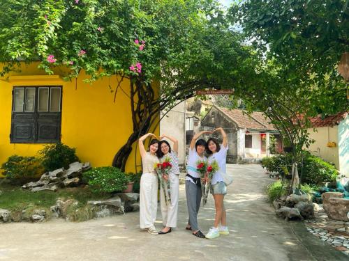 a group of three women standing in front of a yellow house at Trang An Elegant Homestay in Ninh Binh