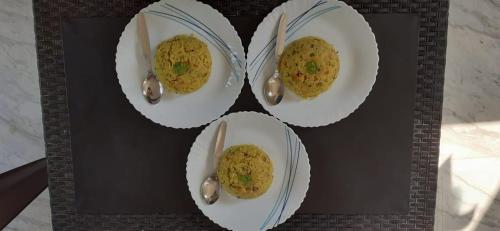 four plates of food with spoons on a table at Ecoark Farmstay in Cuncolim