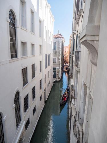 a canal between two buildings with a boat in it at EGO' Boutique Hotel - The Silk Road in Venice