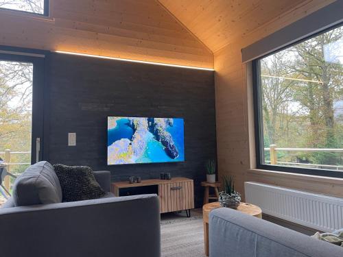 a living room with a couch and a flat screen tv at Chalet Keano - Nieuwe Luxe Chalet dichtbij Durbuy ! in Durbuy