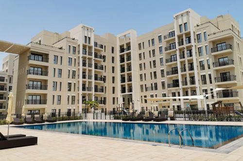 a large apartment building with a large swimming pool at Lovely calm 3BR Apt Easy Accessibility to central Dubai with huge balcony and pool view Town Square in Dubai