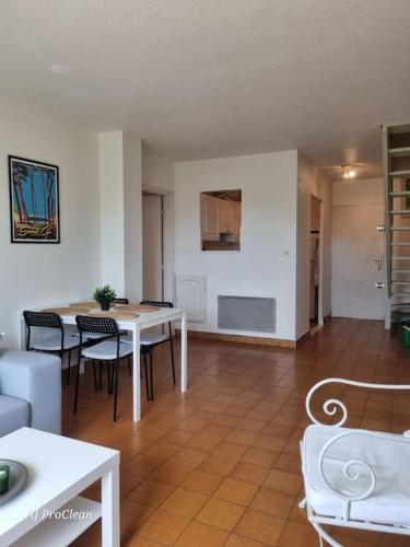 un salon avec une table et des chaises blanches dans l'établissement Armence, maison vue mer avec petit jardin et terrain de tennis - By AURAconciergerie, aux Lecques
