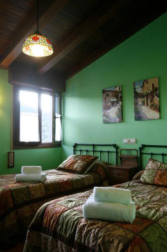 two beds in a room with green walls at Casa Felisa Pirineo Aragonés in Santa Eulalia de Gállego