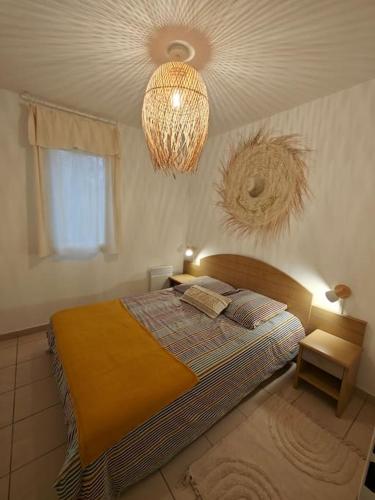 une chambre avec un lit et un lustre dans l'établissement Maison avec piscine, tennis, à Ondres