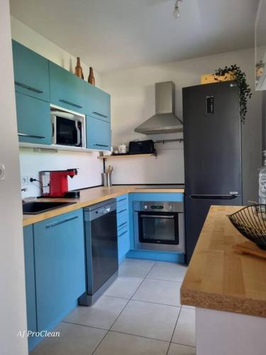 - une cuisine avec des armoires bleues et un réfrigérateur noir dans l'établissement La Petite Cigale, grand balcon à 10min du Circuit Paul Richard et 15min de la mer - By AURAconciergerie, au Beausset