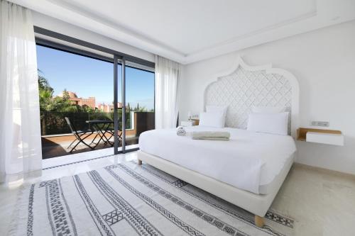 a white bedroom with a large bed and a large window at DAR KAYIS & LAILA in Marrakesh