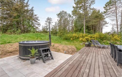 a wooden deck with a hot tub and chairs at 4 Bedroom Amazing Home In Blokhus in Blokhus
