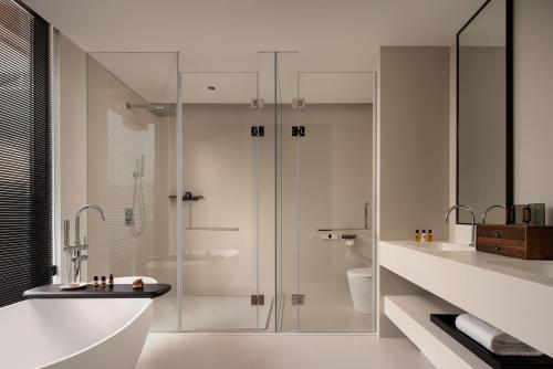 a white bathroom with a shower and a sink at Rong Unique Hotel-Banyan Lake Scenery in Guilin