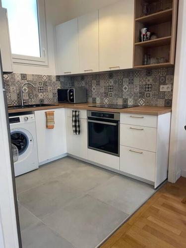 une cuisine avec des armoires blanches et une laveuse et une sécheuse dans l'établissement Appartement Niçois, à Nice