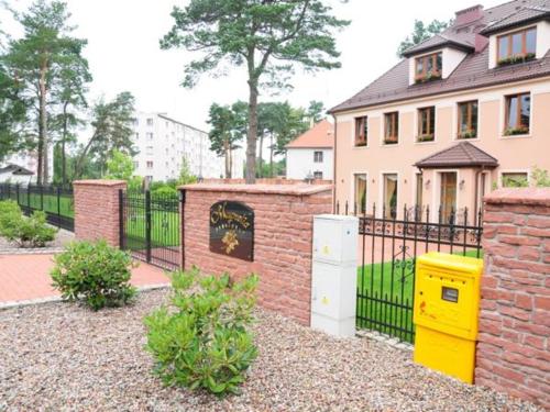 a house with a brick fence and a yellow box at SAS Militaria dla 2 par 2 pokoje 4 osoby in Borne Sulinowo