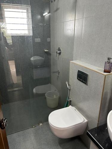a bathroom with a toilet and a glass shower at Thottan house in Trichūr