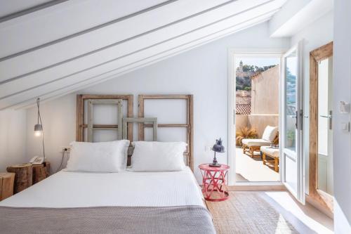 a bedroom with a white bed and a balcony at Amymone Suites in Nafplio