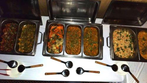 four containers of food on a table with spoons at Desert Moments Camp in Al Wāşil