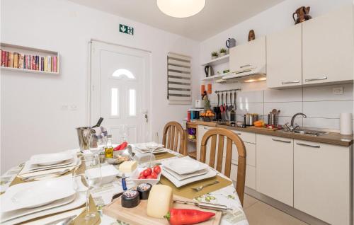 kuchnia ze stołem oraz kuchnia z białymi szafkami w obiekcie Amazing Apartment In Stara Novalja w mieście Stara Novalja