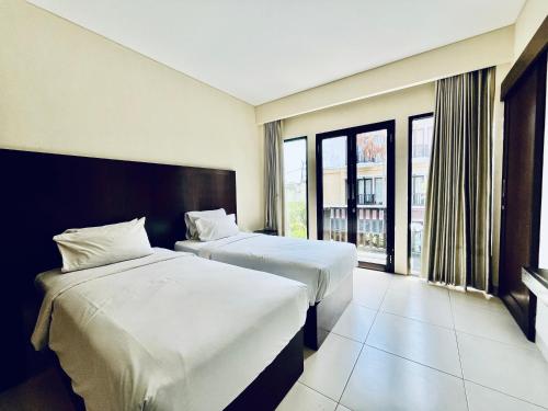 a hotel room with two beds and a window at Suris Boutique Hotel in Kuta