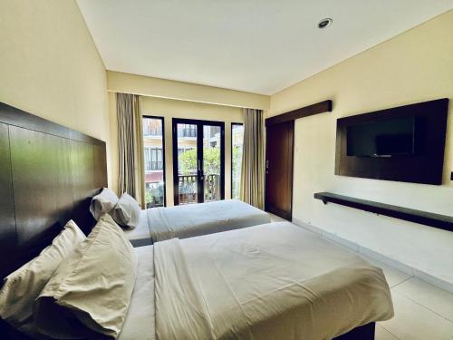 a hotel room with two beds and a flat screen tv at Suris Boutique Hotel in Kuta