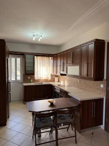 a kitchen with wooden cabinets and a table with chairs at Relaxing home in Taxiárkhai