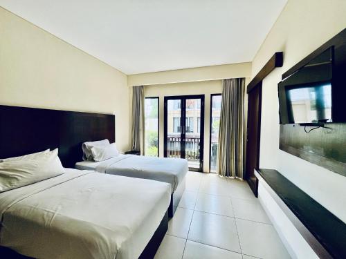 a hotel room with two beds and a flat screen tv at Suris Boutique Hotel in Kuta