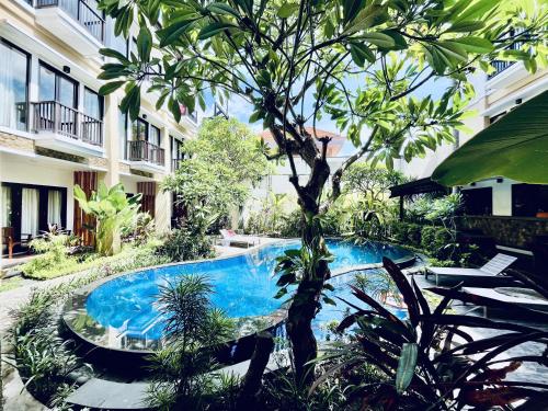 a swimming pool with a tree in a courtyard at Suris Boutique Hotel in Kuta