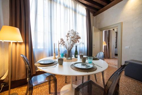 a dining room table with chairs and a white table with plates and candles at Venice Dream - Il più centrale, idromassaggio in camera, ascensore - 10 min da Rialto e San Marco in Venice