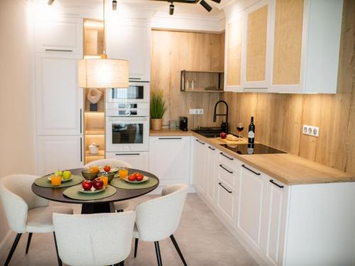 a kitchen with white cabinets and a table with fruit on it at MyFreedom Panorama Cubana Apartment in Alsóörs