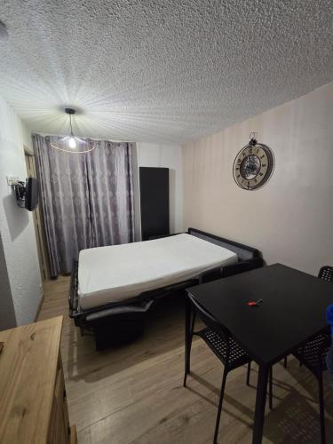 Cette chambre comprend un lit, une table et une horloge. dans l'établissement Risoul 1850 appartement 4 personnes proches pistes., à Risoul