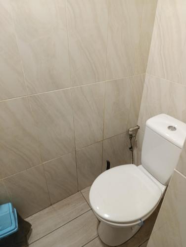 a bathroom with a toilet and a tiled wall at Хостел Sweet Home in Mykolaiv