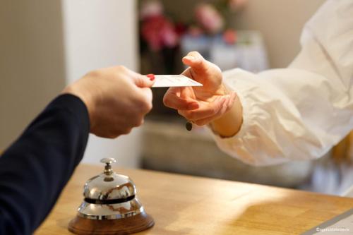 a person holding up a piece of paper with a bell at Boutique Hôtel Entraigues in Uzès