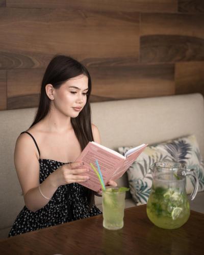a woman sitting at a table reading a book at MIRAMAR Apart Hotel & SPA in Aktau