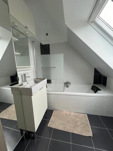 une salle de bain avec un lavabo et une baignoire dans l'établissement Maison bord de mer, plage 160m, à Guissény