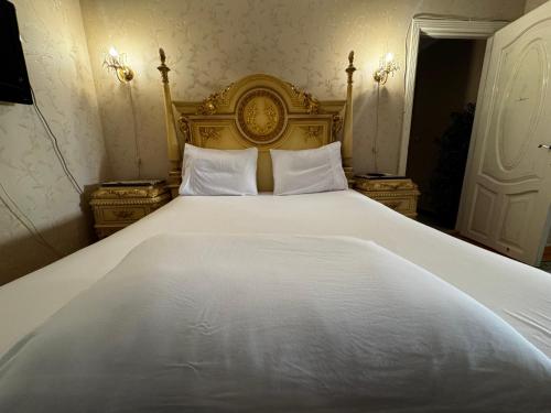 a large white bed with a gold headboard and pillows at center of Alexandria in Alexandria