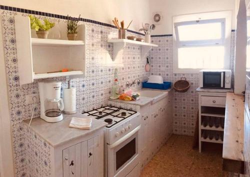 a white kitchen with a stove and a sink at Havre de Montemar Vue et Piscine in Benissa