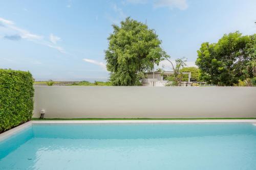 a swimming pool in front of a white fence at Venice Beach Village Hua Hin Pool Villa in Cha Am