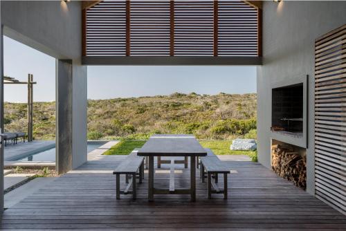 a wooden deck with a table and benches on a house at Romansbaai Collection in Gansbaai