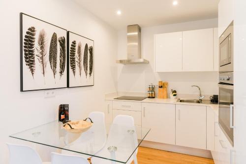 a kitchen with a glass table and white cabinets at Fatima`s House in Funchal