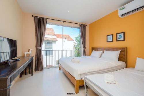 a bedroom with two beds and a desk and a balcony at Venice Beach Village Hua Hin Pool Villa in Cha Am
