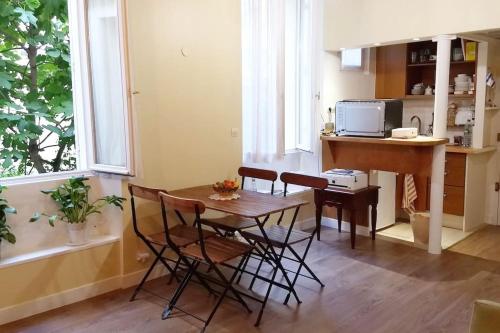 une cuisine avec une table et des chaises dans une pièce dans l'établissement IMPECCABLE & TYPICAL STUDIO in THE MARAIS, à Paris