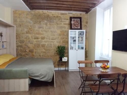 - une chambre avec un lit, une table et un mur en briques dans l'établissement IMPECCABLE & TYPICAL STUDIO in THE MARAIS, à Paris