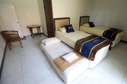 a room with two beds and a chair and a table at Katumbiri Resort in Bogor