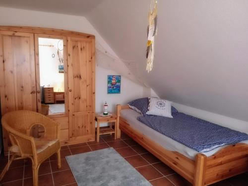 a bedroom with a bed and a chair in a room at Drei-Insel-Blick Neßmersiel in Neßmersiel