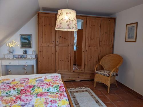 a bedroom with a bed and a chair and a chandelier at Drei-Insel-Blick Neßmersiel in Neßmersiel