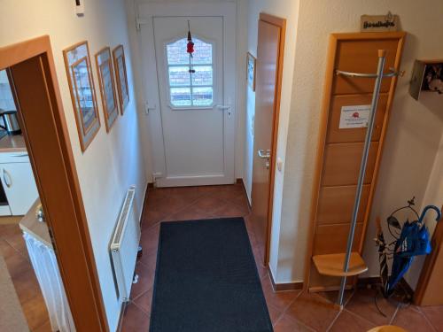 a hallway with a white door and a black rug at Drei-Insel-Blick Neßmersiel in Neßmersiel